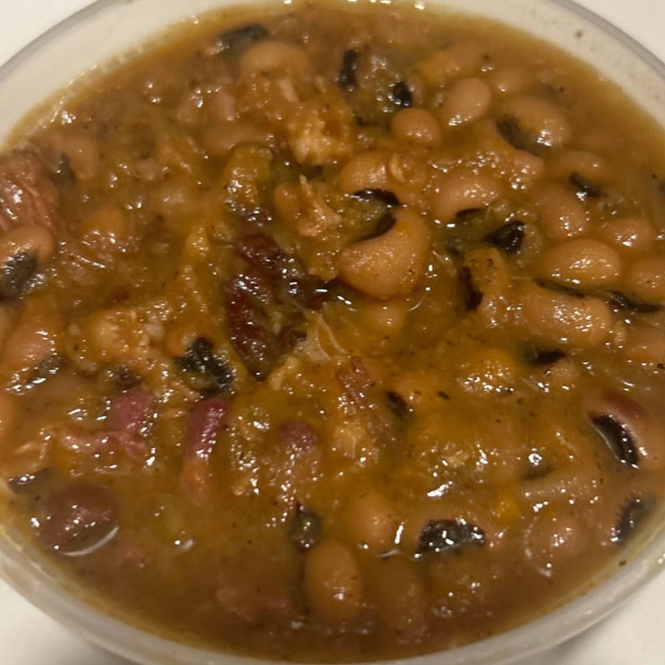 Close-up of Aunt Berta's Kitchen's soul food black-eyed peas with meat in a white bowl.