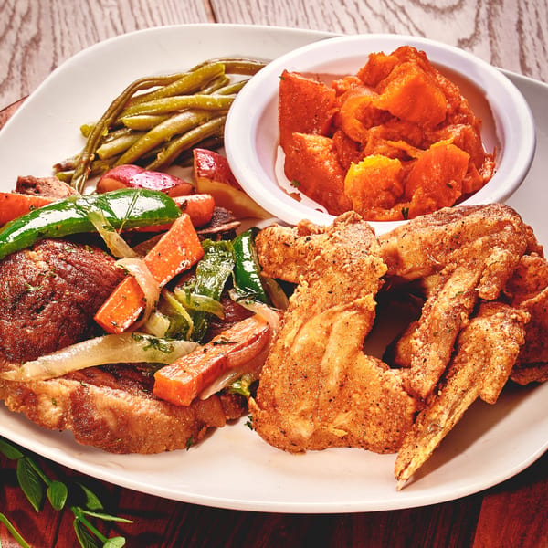 A plate of fried chicken, green beans, sweet potatoes, and roasted vegetables.