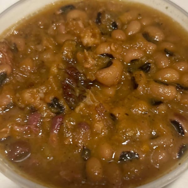 A close-up of Aunt Berta's Kitchen's soul-food black-eyed peas with ham hocks in a rich brown sauce.