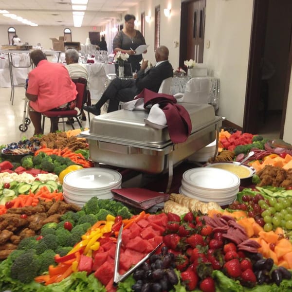 A large soul-food buffet spread with fried chicken, vegetables, fruit, and a chafing dish.
