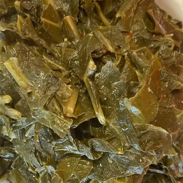 Close-up of Aunt Berta's Kitchen's soul-food collard greens, glistening with seasoning.
