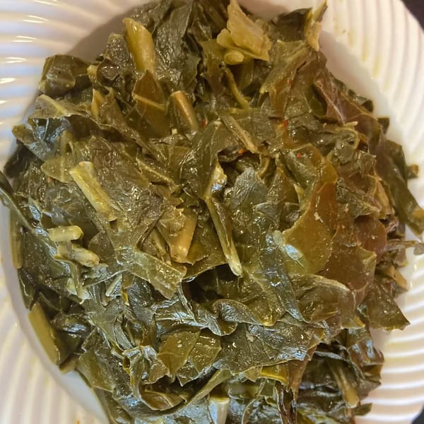 Close-up of Aunt Berta's Kitchen's collard greens, a soul food staple, served in a white bowl.